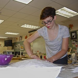 Senior Maddy Boyce works on a shield, a part of her Halloween costume. Photo by Abigail Carbonneau