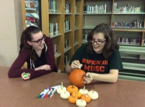Sophomore, Brianna Maloney and Senior, Sarah Biliter expressing their art skills, by decorating pumpkins at Thursdayâ€™s Halloween movie event hosted by Book Club. Photo by Sabrina Martin 