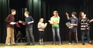 Evelyn Oliver (center), playing Alice Little, and other cast members (left to right) Erik Fliegauf, Jack McCauliffe, Ashley Olafsen, Henry Vumbaca, and Taylor Forsmo prepare the "Growing and Shrinking scene" for the original HHS production of Uncommon Nonsense. The scene is based in a theatrical game in which a new actor enters the stage to create a new scene. As more players are added and new scenes emerge, they eventually exit the stage and the scenes are recycled. Photo by Blair Guild