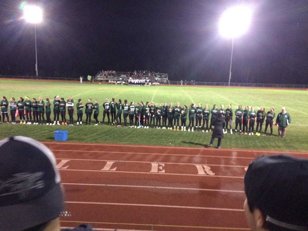 The Hopkinton High School senior powderpuff team prepares for the big game as they listen to the National Anthem. Photo by Alli McNulty.