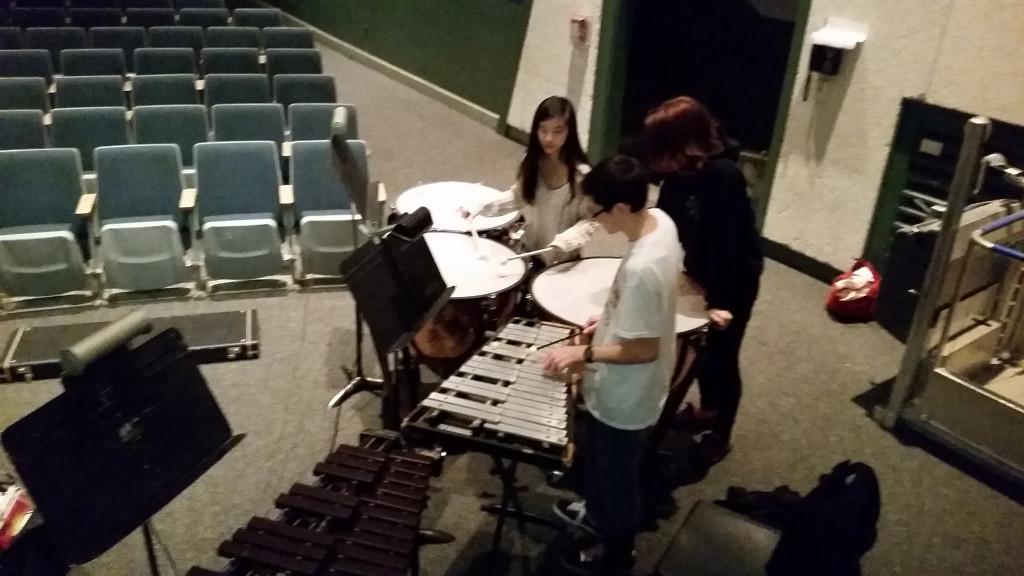 Pit band members Samuel Faucher, Brian Best, and actor Clare Wu looking over the score to the show.