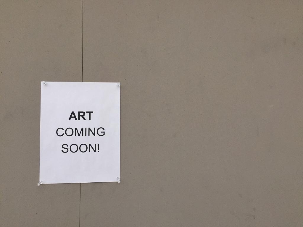 A sign hangs on a bulletin board in the atrium that announces upcoming art projects to be displayed. Photo by Emma Zack.