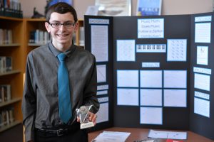 Junior Brian Best proudly stands beside his third-place winning project, "Music Math: Does Music Follow a Zipfian Distribution?" Photo courtesy of Fred Haas.