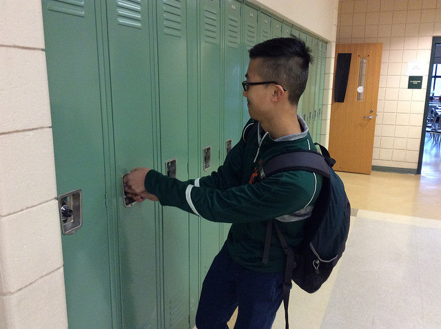 Freshman Young Wang struggles to open his jammed locker before classes start. Photo by Josh Normandeau. 