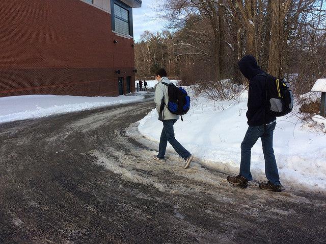 Senior Aidan Curry and sophomore Declan Curry rush from water towers parking lot to the high school just before the bell rings. Photo by Josh Normandeau. 